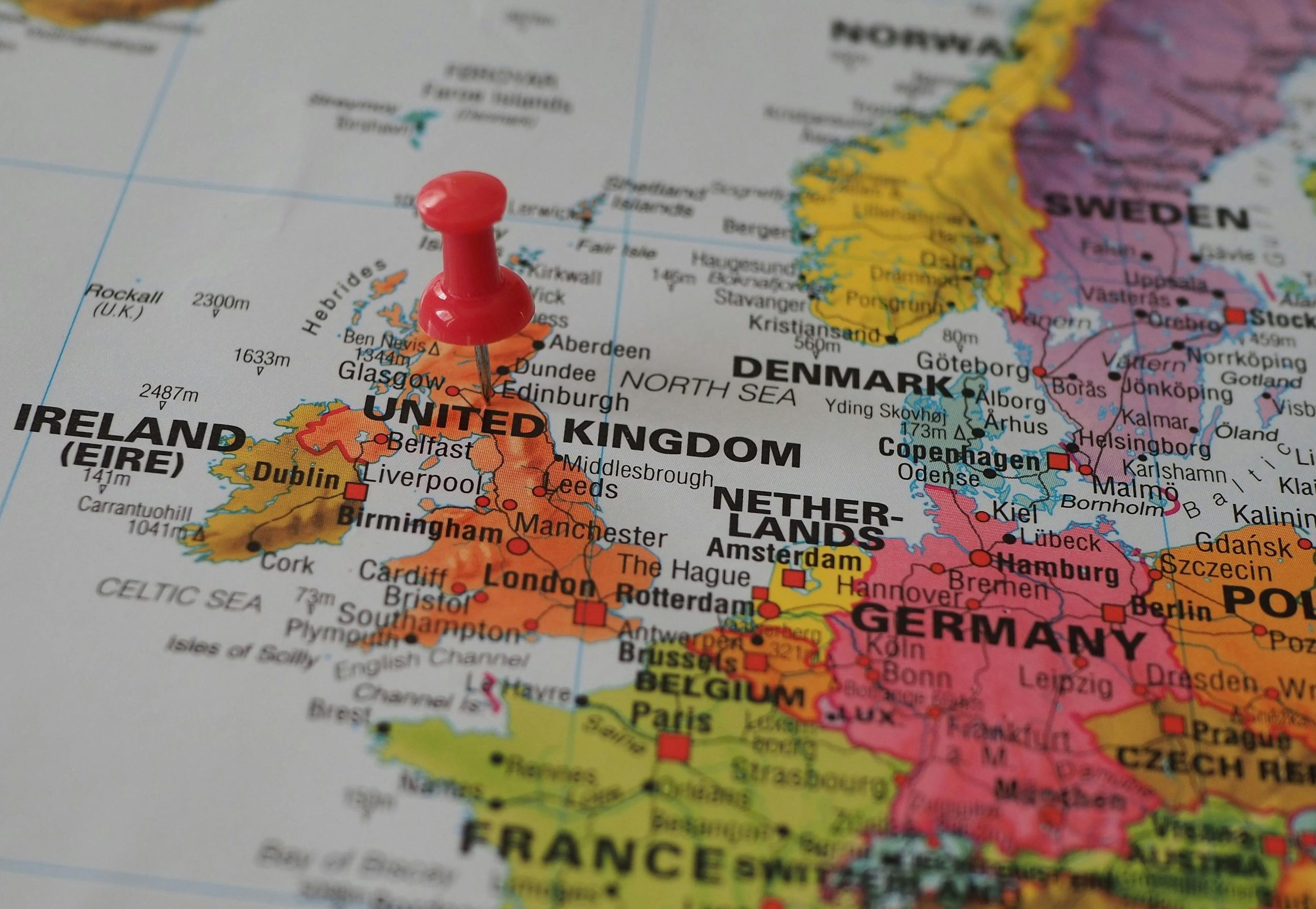 Close-up of a European map highlighting the UK with a red pin, perfect for geography themes.